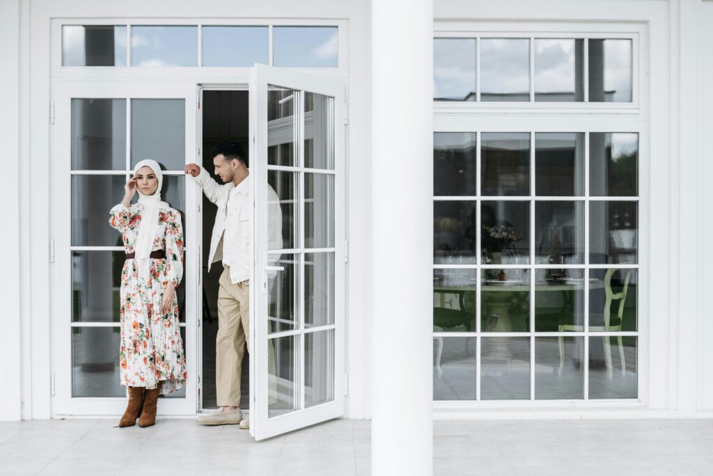A couple in front of a French door and window.