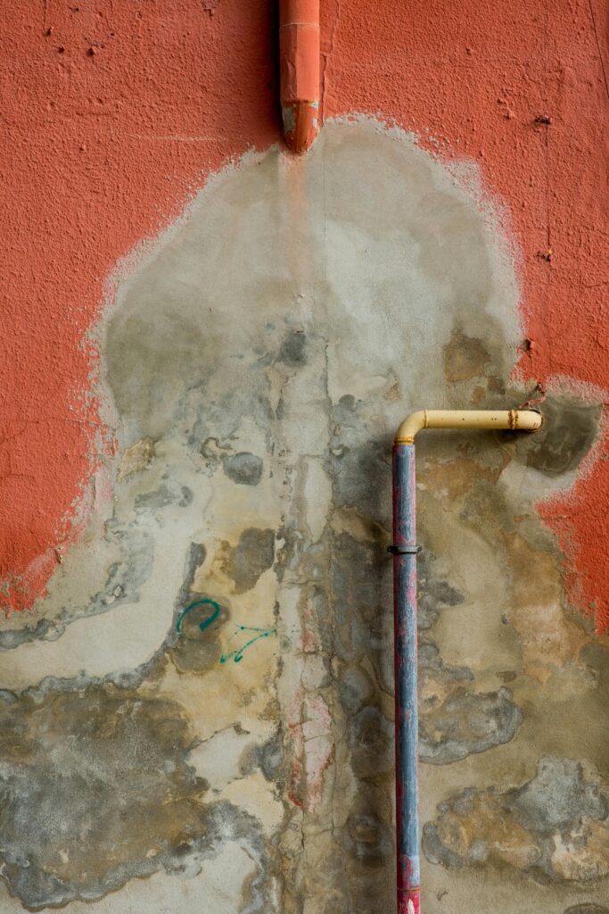 A wall with a pipe and water damage.