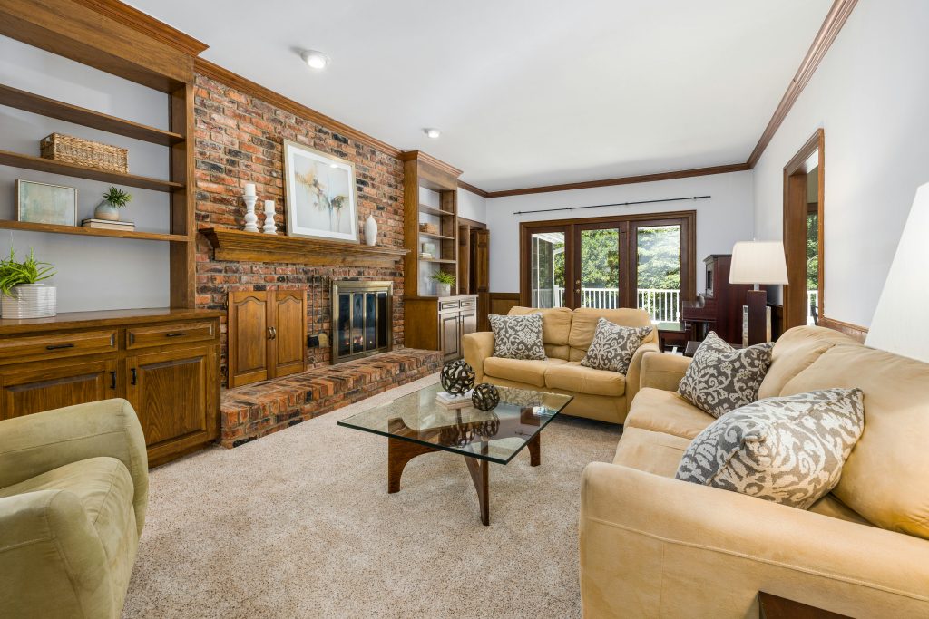 a dated-looking living room with wall-to-wall carpet flooring.