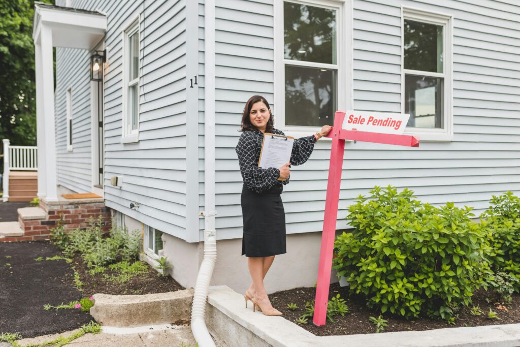A woman holding a 'sale pending' sign.