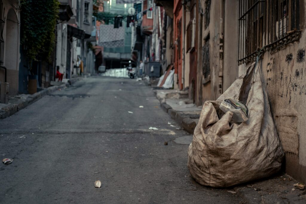 A garbage sack on a dirty street.