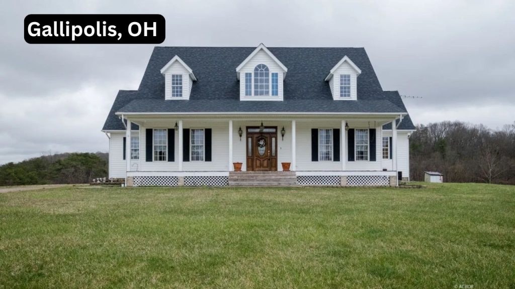 A classic white farmhouse with black shutters and a large front porch, set in a grassy field in Gallipolis, Ohio.