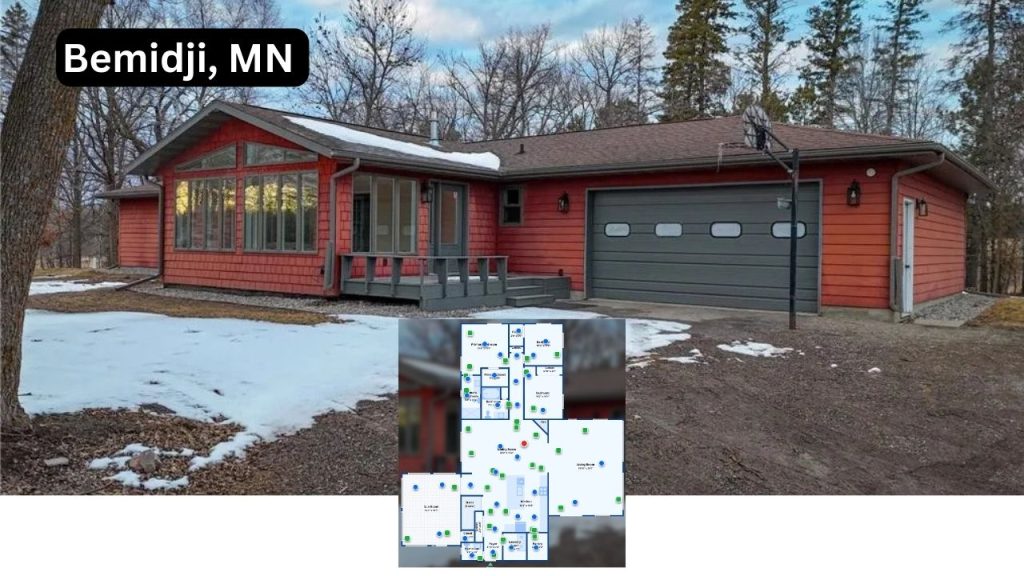 Red cabin-style home with large windows, front porch, and attached garage in snowy woodland setting.