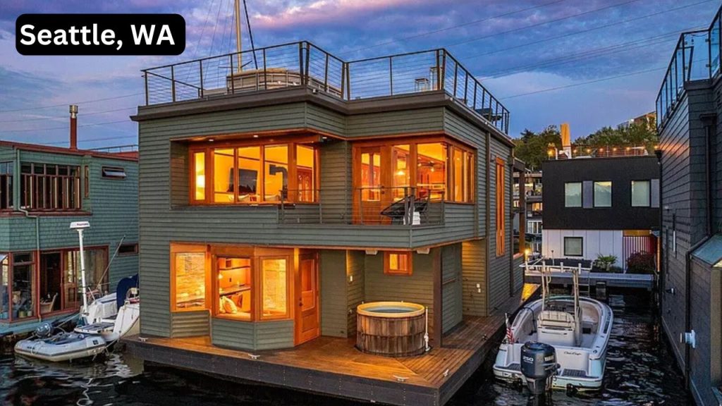 Modern two-story floating home in Seattle with warm interior lights, rooftop deck, and docked boats.