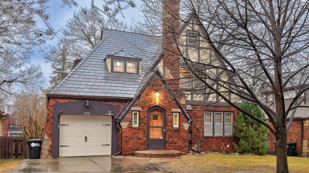 Tudor-style brick home with steep roof, dormer, and arched front door.