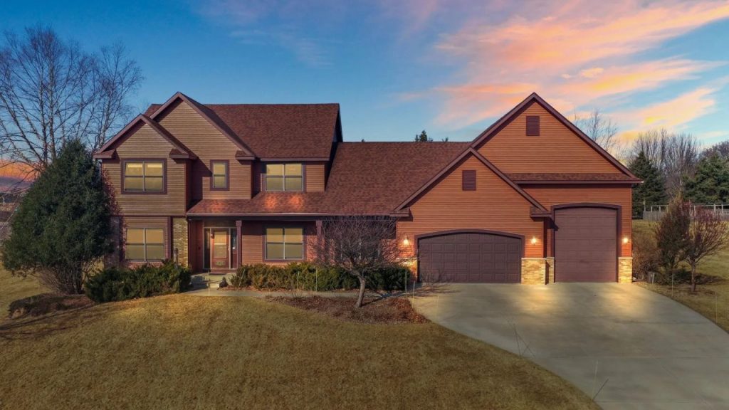 Two-story home with gabled roof and brown siding at sunset.