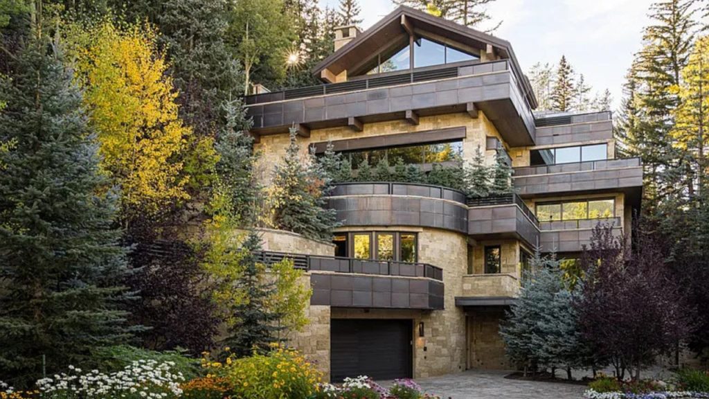 A beautiful multi-family home surrounded by trees and flowers, showcasing stone and metal architecture.