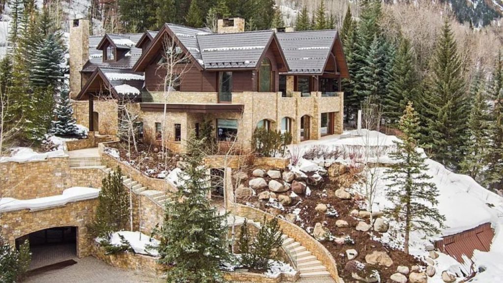 Sophisticated stone home nestled in Aspen’s snowy landscape, surrounded by greenery.