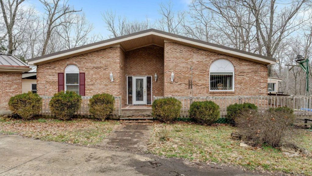 Brick ranch-style house with gable roof and arched windows.