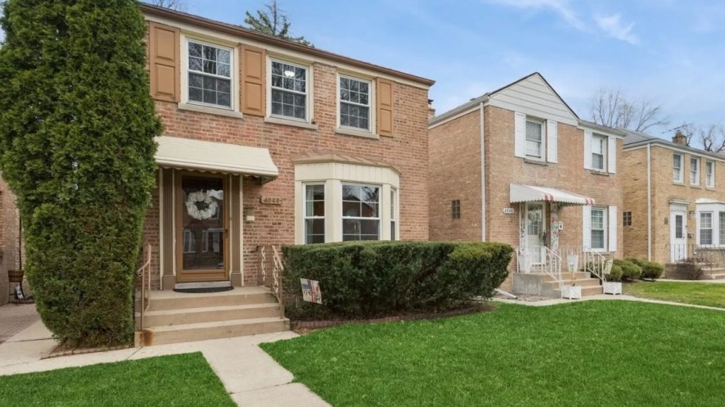 Brick colonial home with bay window and front steps.