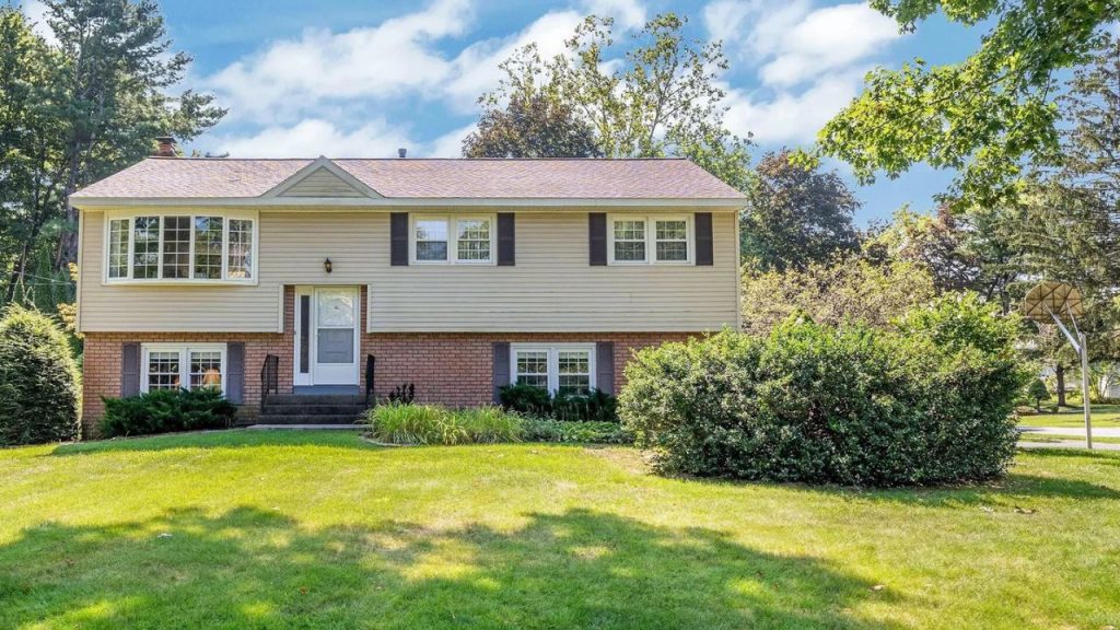 Split-level colonial-style home with brick and siding exterior on a sunny lawn.