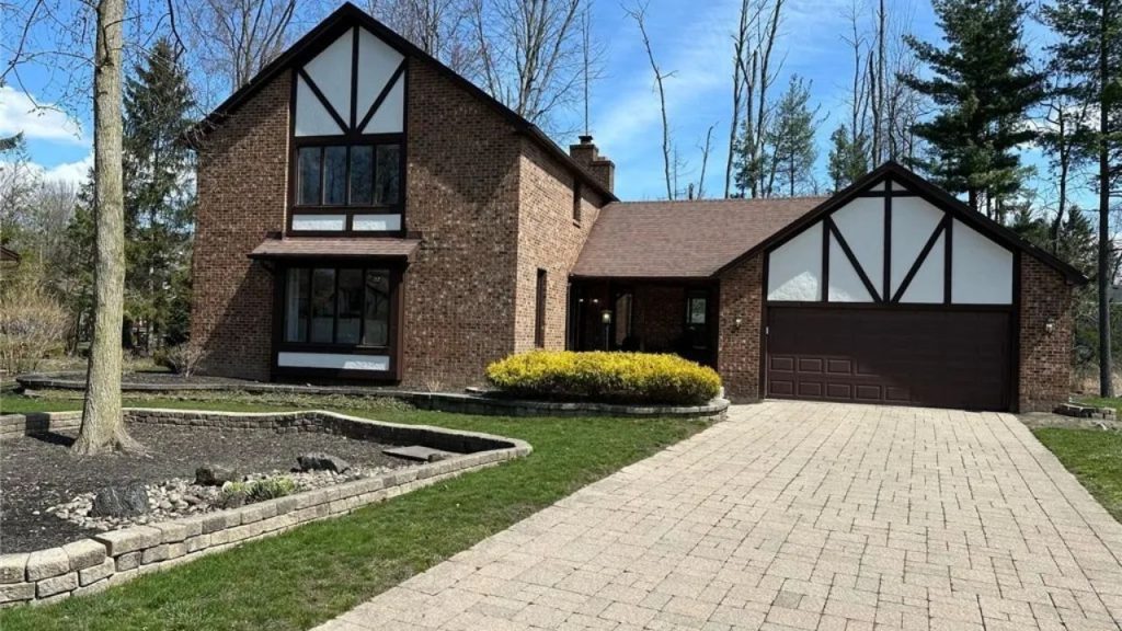 Tudor-style brick home with pitched roof and modern landscaping.