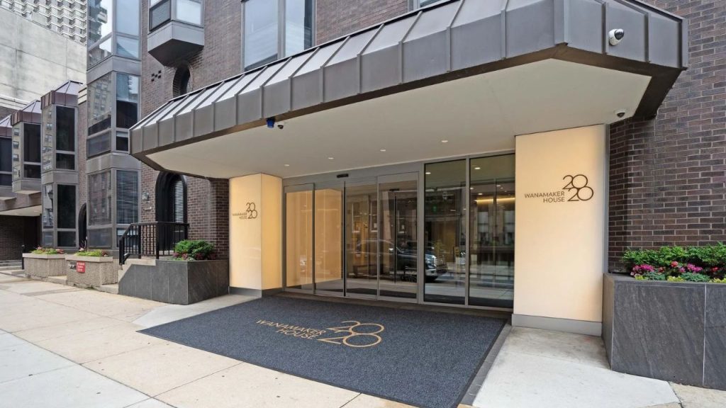 Modern entrance of Wanamaker House with glass doors and geometric canopy.