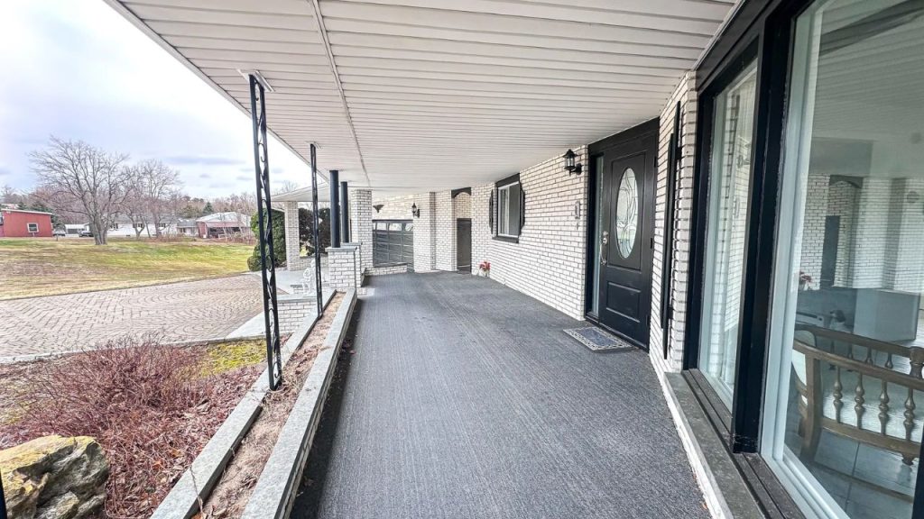 Wide covered front porch with white brick exterior and black accents.