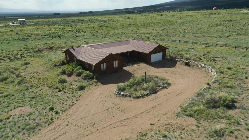 Ranch-style home with a metal roof surrounded by open land.