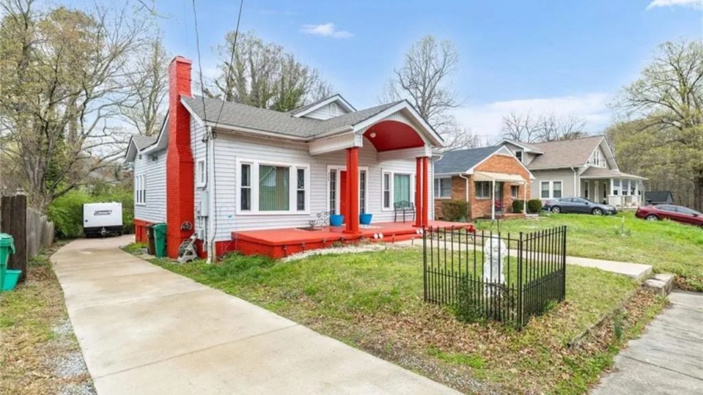 Colorful craftsman home with red porch and chimney on a tree-lined street.