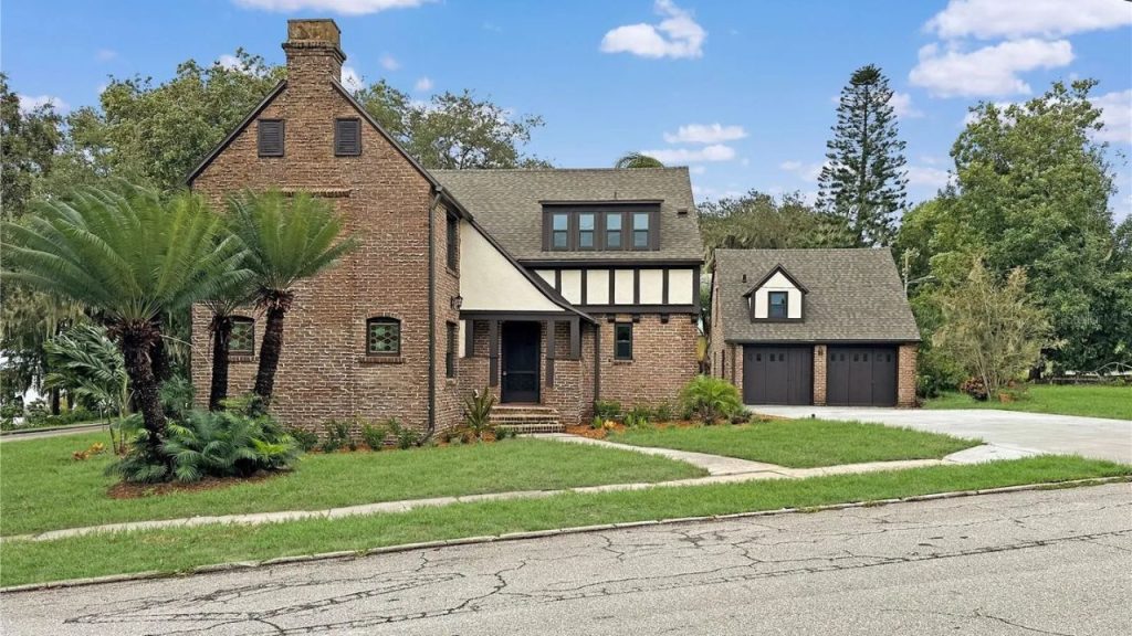 Tudor-style brick home with a triple garage and palm landscaping in Eustis, FL.