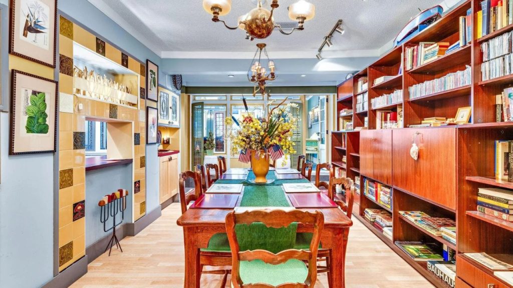 Bright dining room with bookshelves, wood table, and eclectic decor.