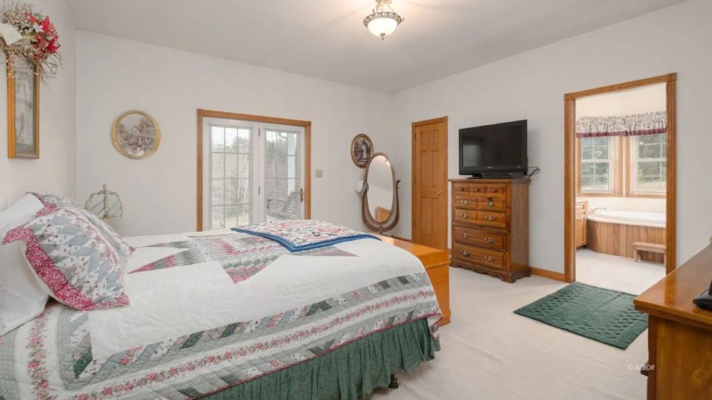 Cozy bedroom with quilted bedding, wooden furniture, and an en-suite bath.