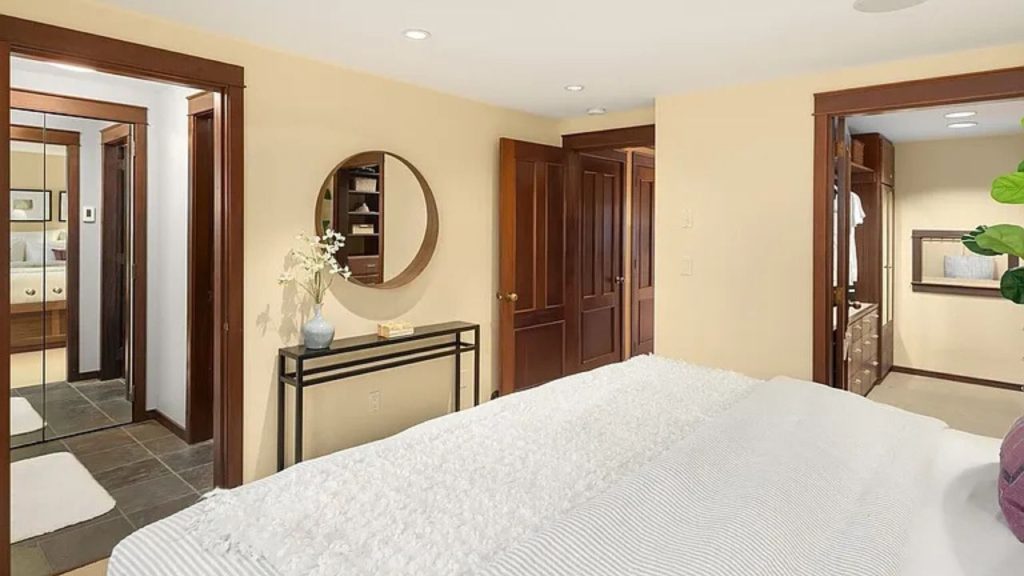 Bedroom with walk-in closet, wood doors, and mirror over console table.