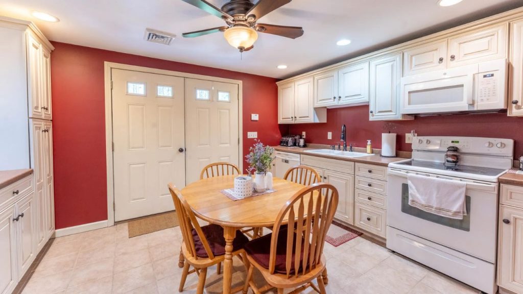 Cozy kitchen with red walls, cream cabinetry, and a wooden dining table.