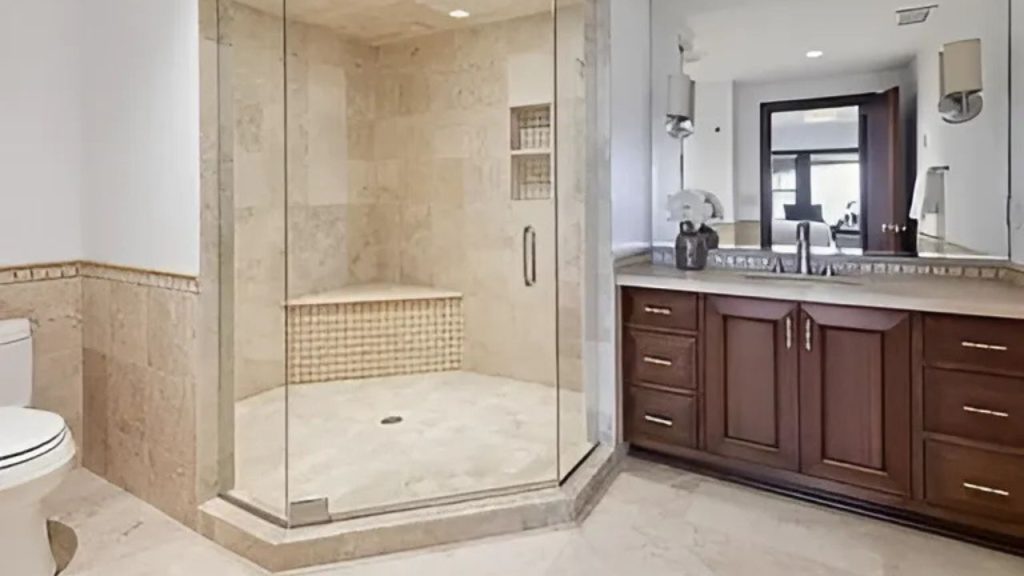 A calm bathroom with a glass shower, wood vanity, and natural light.