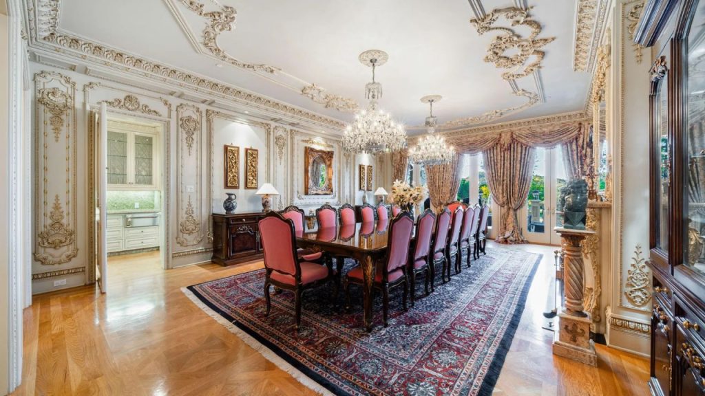 A regal dining room with chandeliers, red chairs, and ornate decor.