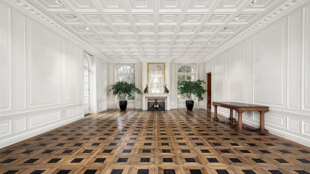 A spacious hall with coffered ceilings, parquet floors, and a central fireplace.