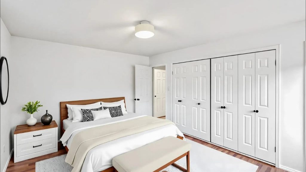 A peaceful bedroom with a wooden bed, white closet doors, and a cozy bench, featuring soft lighting and greenery.