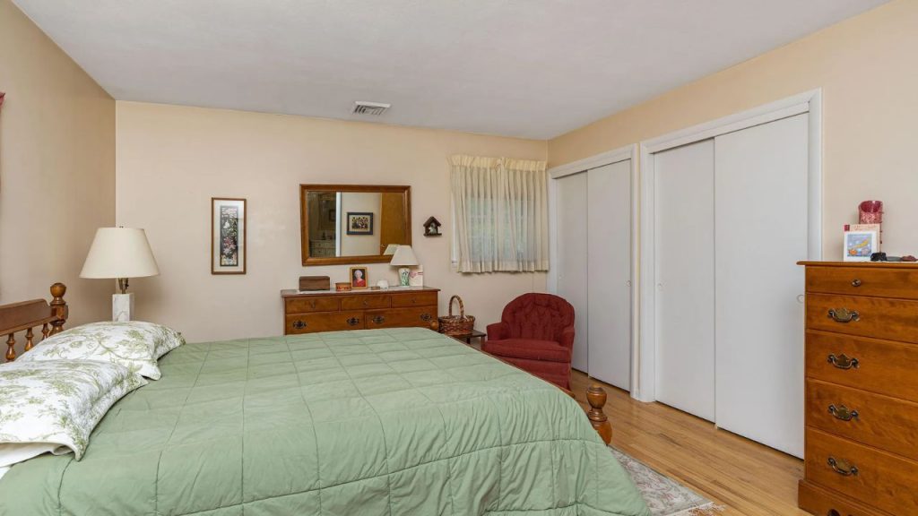 Comfortable bedroom with green bedding, wood furniture, and a red armchair.