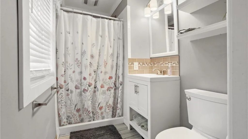 Bright bathroom with floral shower curtain and soft gray walls.
