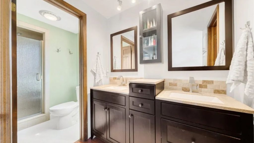 Bathroom with double sinks, dark cabinets, and walk-in shower.