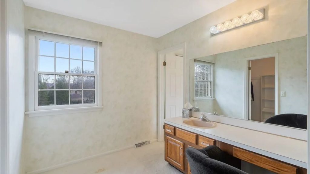 Bright vanity area with wood cabinets and large mirror.