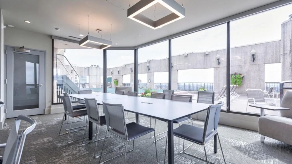 Rooftop meeting room with large windows, modern table, and terrace access.