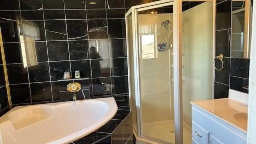 Black-tiled bathroom with a soaking tub and glass shower.