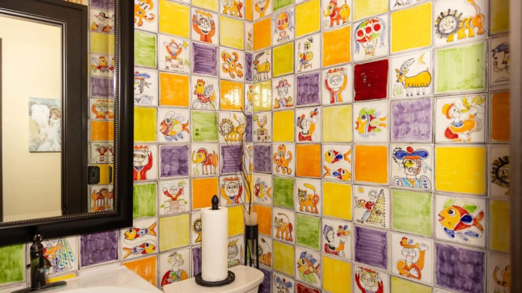 Brightly colored bathroom with hand-painted tiles featuring playful illustrations.