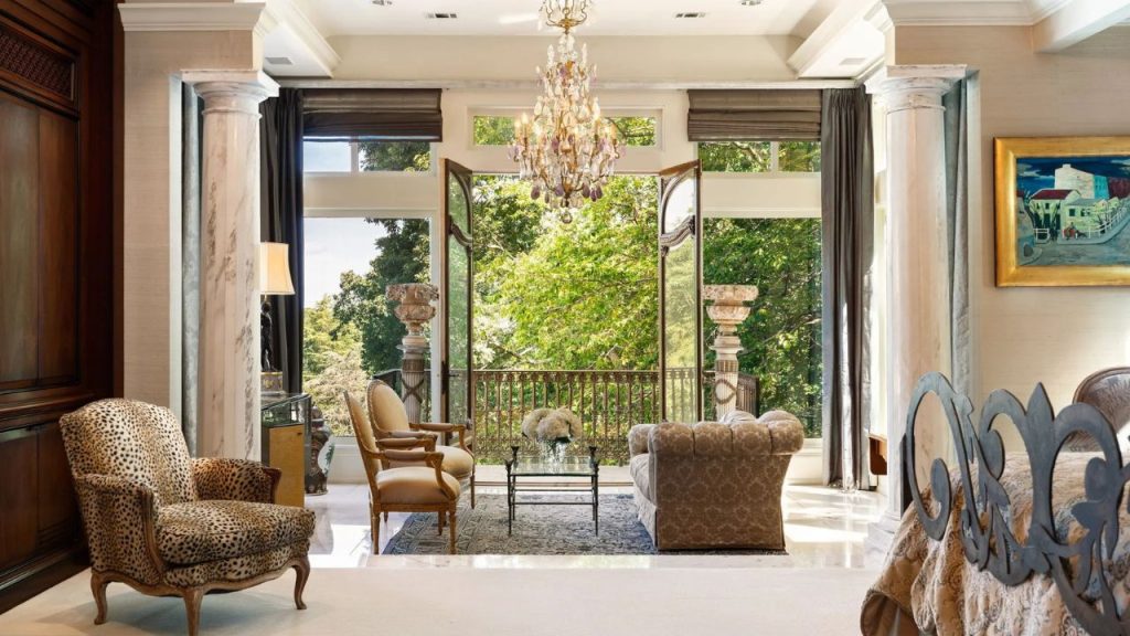 Elegant indoor sitting area with open balcony doors, marble columns, and chandelier.