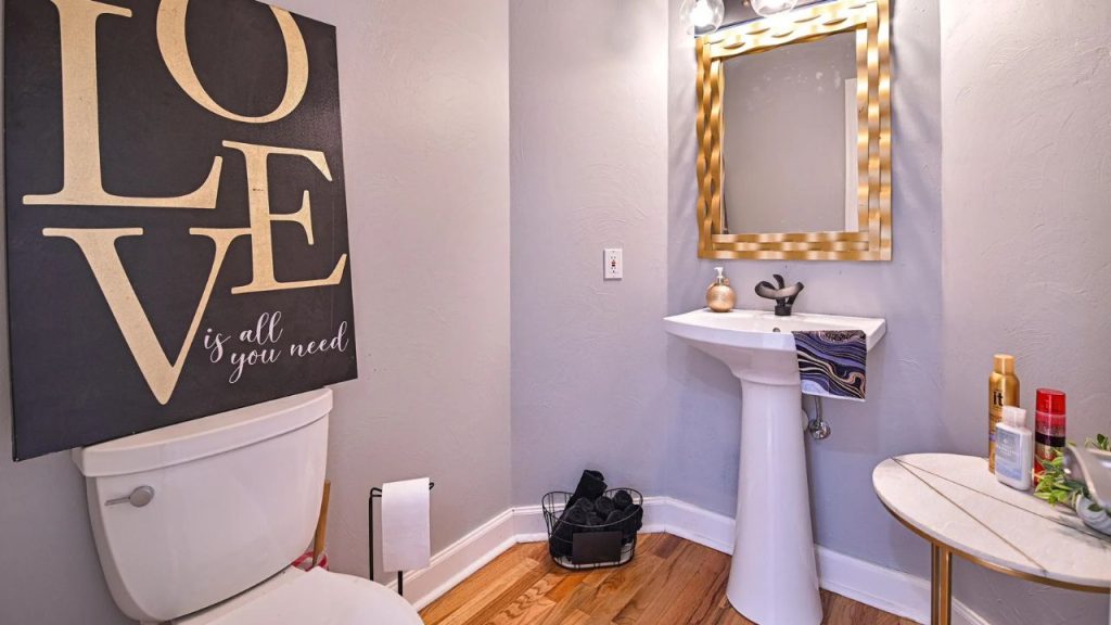 Elegant powder room with a pedestal sink, gold mirror, and stylish decor.