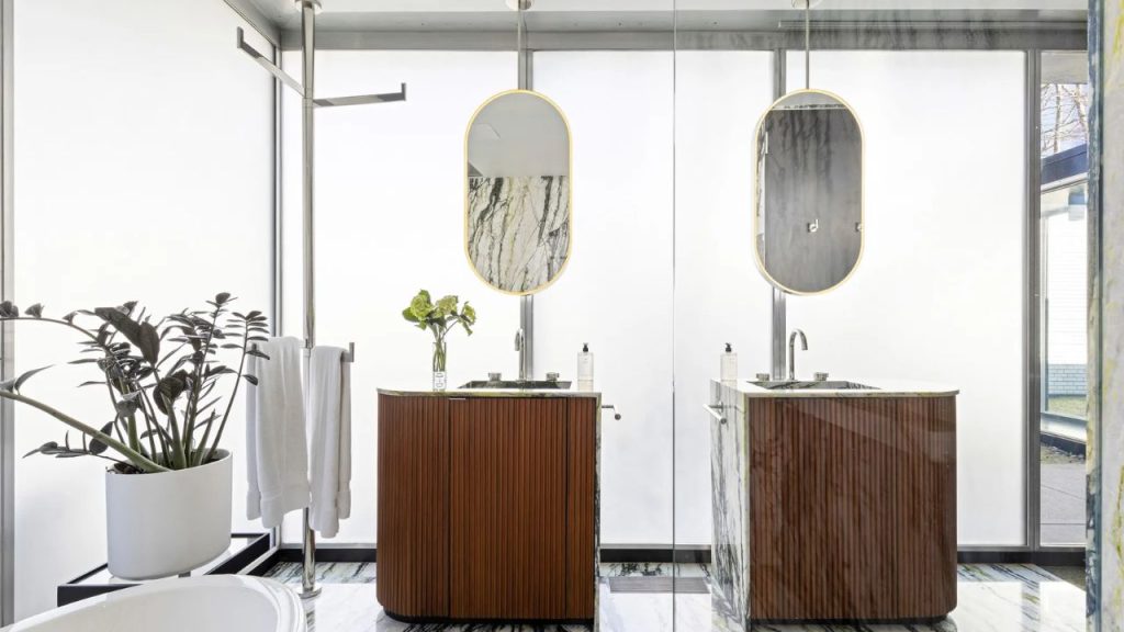 Bright, modern bathroom with double vanities and elegant oval mirrors.
