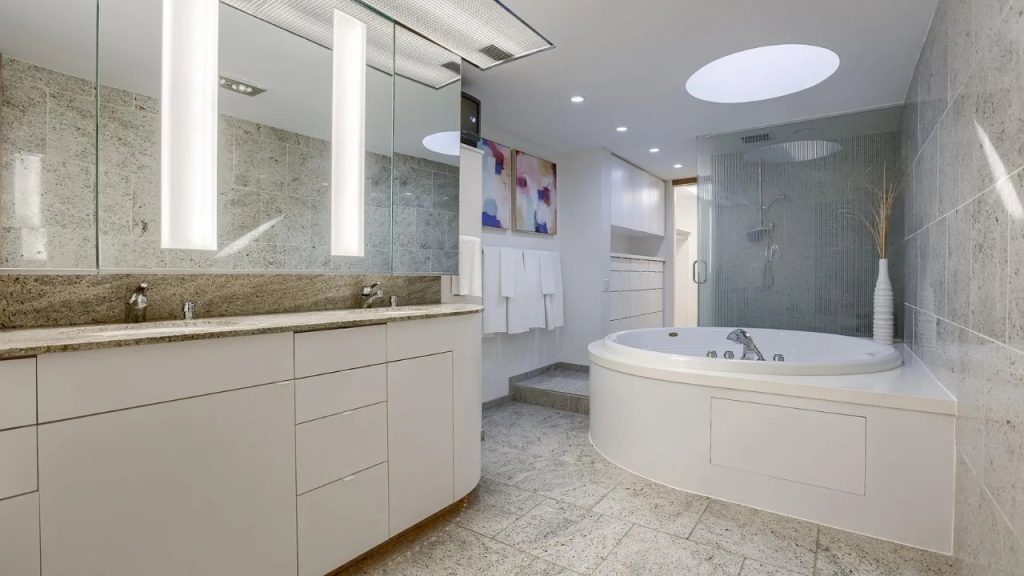 Serene bathroom with round tub, skylight, and twin vanities.