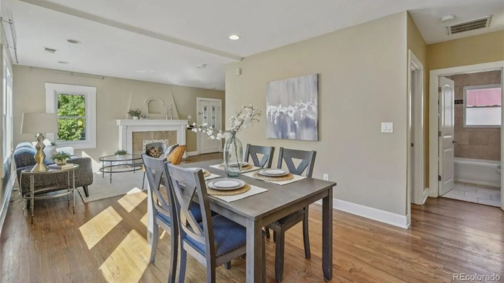 Bright dining and living area with fireplace and hardwood floors.