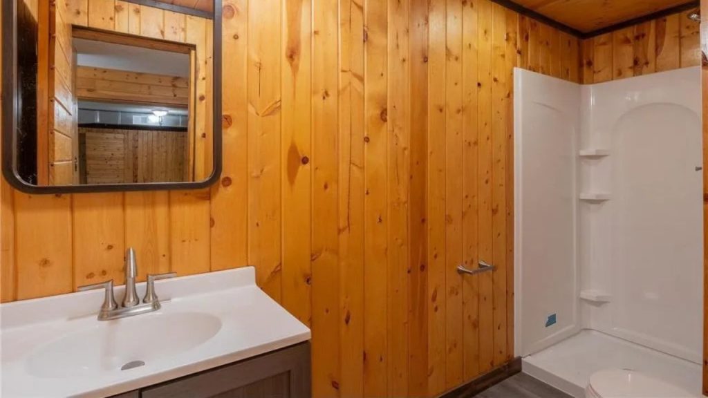 Wood-paneled bathroom with white vanity and shower stall.