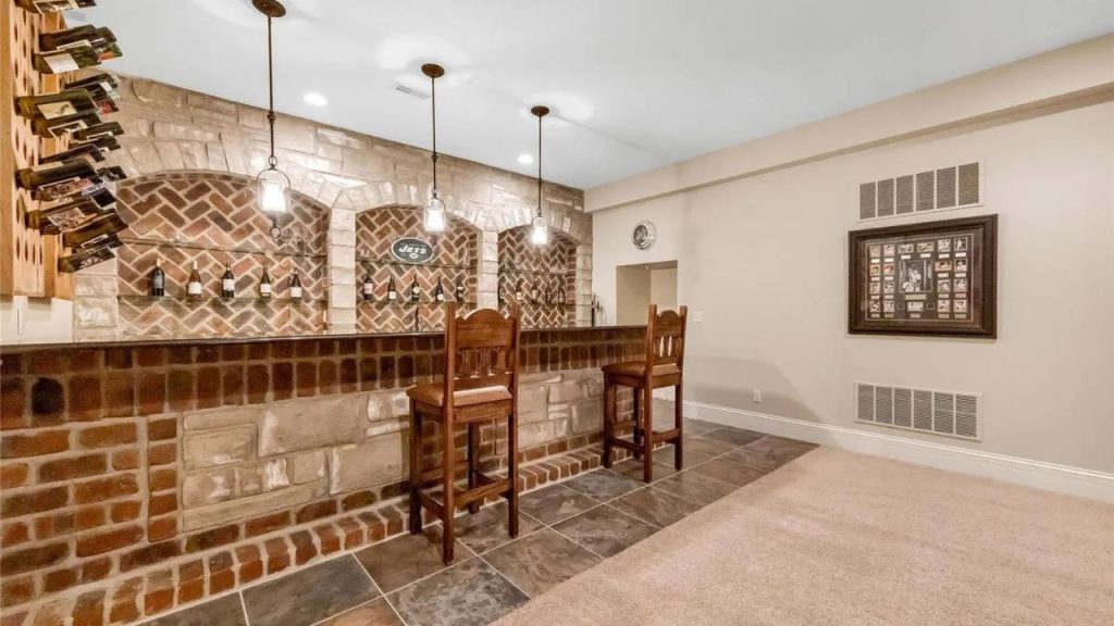 A rustic home bar with exposed brick, stone accents, and warm lighting.