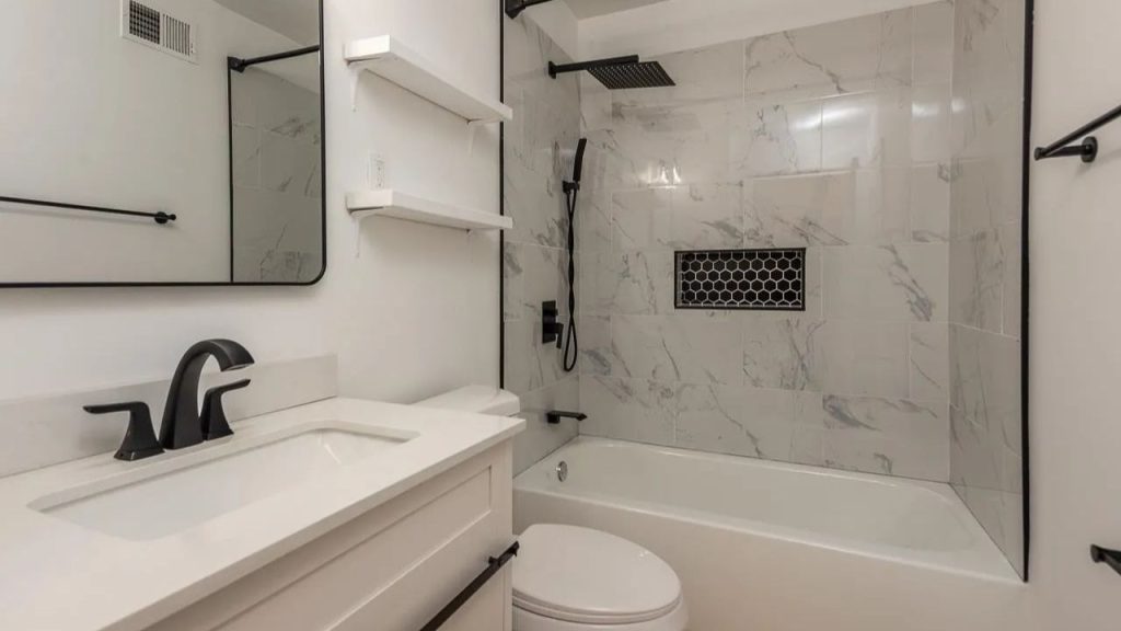 A modern bathroom with marble tiles, a rainfall shower, sleek vanity, and open shelves.