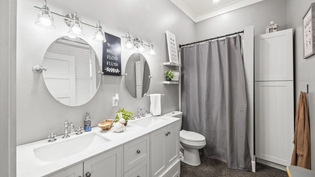 Stylish bathroom with a double vanity, oval mirrors, and soft gray walls.