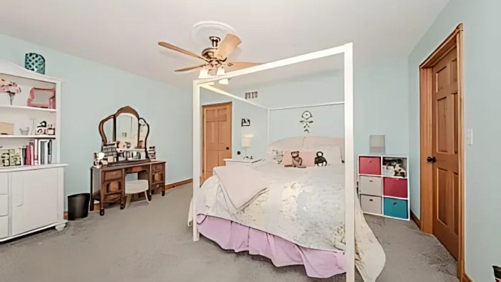A bright kid’s bedroom with a map-covered bed, vanity, and colorful storage.