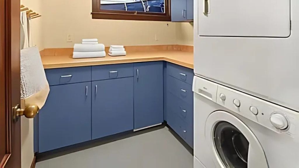 Laundry room with blue cabinets and stackable washer-dryer.