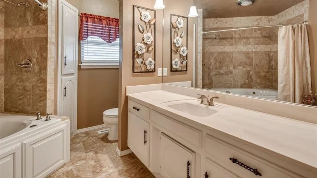 Cozy bathroom with a double vanity, soaking tub, shower, and floral decor, featuring warm tiled floors.