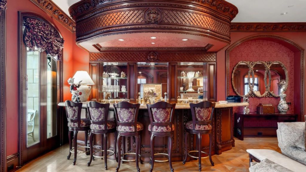 A cozy bar lounge with mahogany paneling, upholstered stools, and ornate mirrors.
