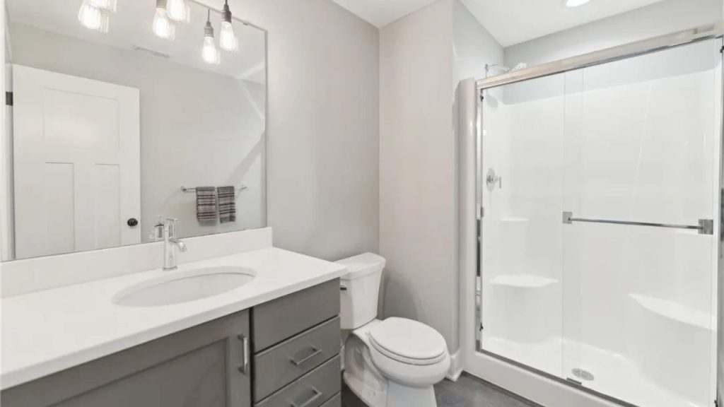 A peaceful bathroom with a gray vanity, glass shower, and modern lighting.